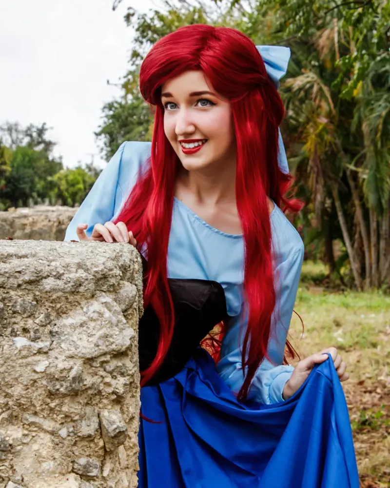 Ariel con su vestido azul junto a un muro de piedra