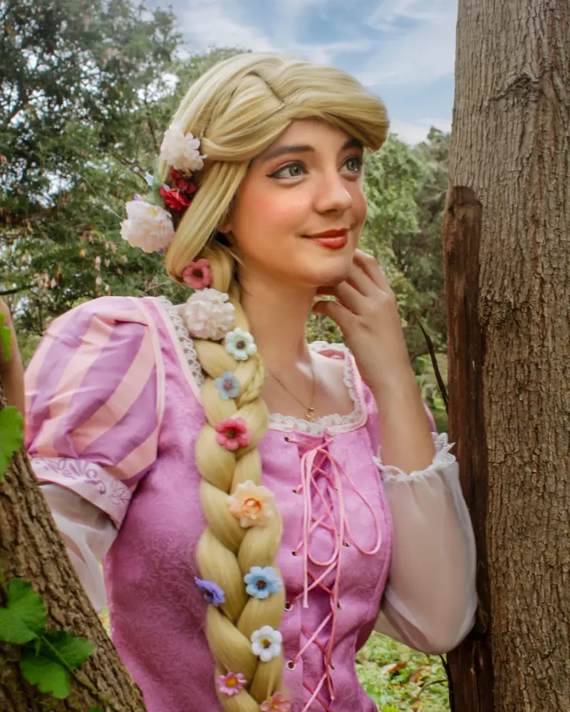 Rapunzel con su trenza de flores junto a un árbol